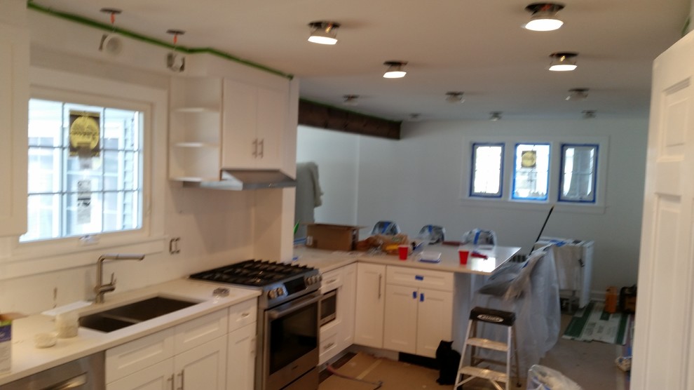 Inspiration for a mid-sized modern galley dark wood floor eat-in kitchen remodel with an undermount sink, recessed-panel cabinets, white cabinets, granite countertops, white backsplash, glass tile backsplash, stainless steel appliances and a peninsula