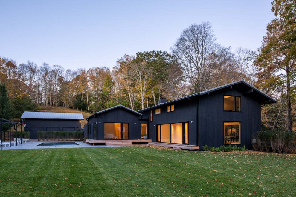 Immagine della villa nera contemporanea a due piani di medie dimensioni con rivestimento in legno, copertura in metallo o lamiera e tetto nero