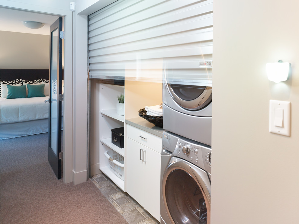 Design ideas for a small contemporary dedicated laundry room in Vancouver with flat-panel cabinets, white cabinets and a stacked washer and dryer.