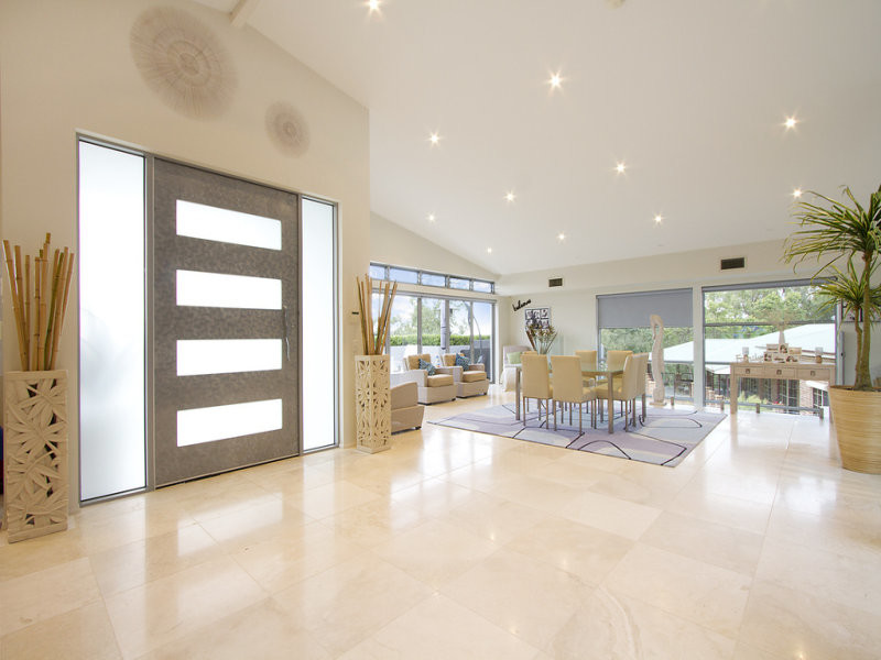 Photo of a large modern foyer in Sydney with beige walls, travertine floors, a pivot front door and a gray front door.