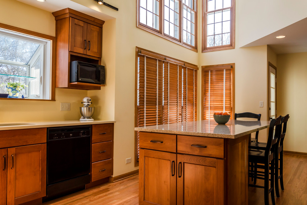 Large transitional l-shaped light wood floor eat-in kitchen photo in Chicago with an undermount sink, recessed-panel cabinets, medium tone wood cabinets, quartz countertops, black appliances and an island