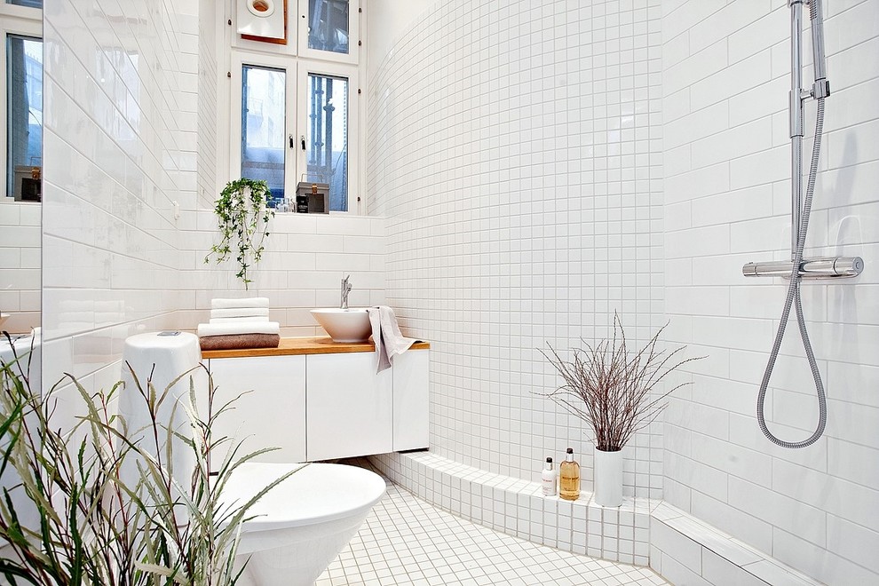 Inspiration for a mid-sized scandinavian 3/4 bathroom in Gothenburg with flat-panel cabinets, white cabinets, a curbless shower, a two-piece toilet, white tile, subway tile, white walls, a vessel sink, wood benchtops and an open shower.
