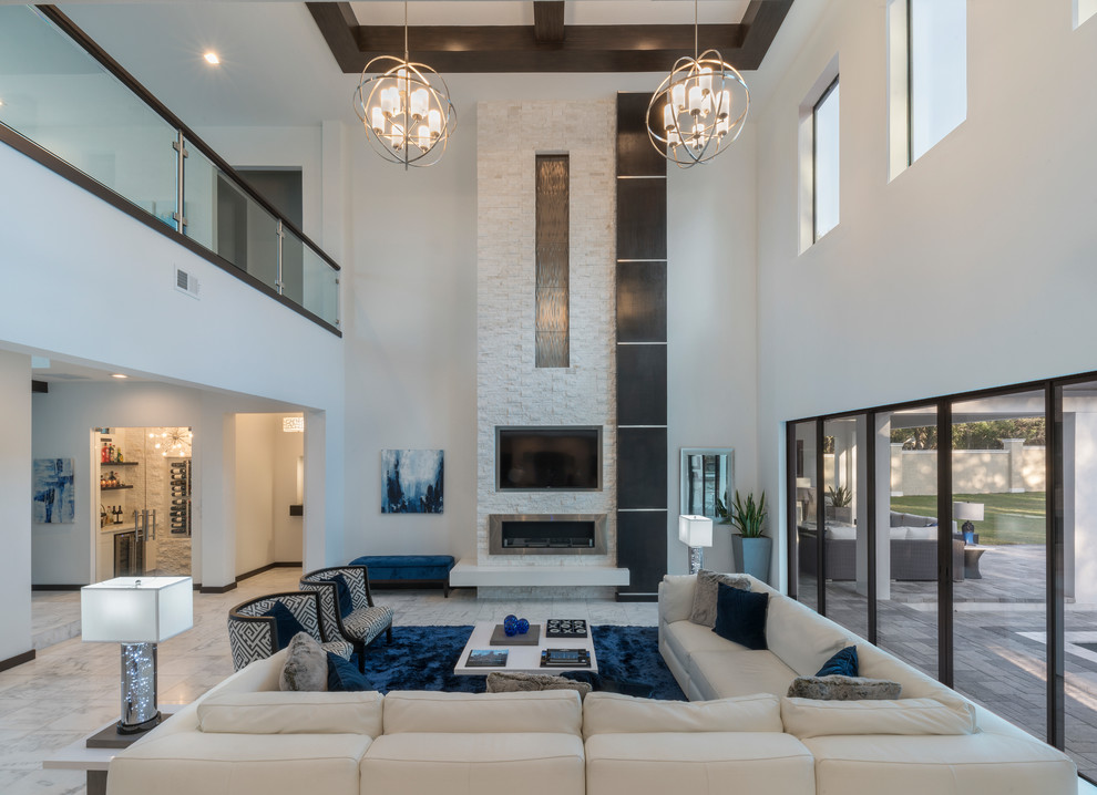 Photo of an expansive contemporary open concept living room in Orlando with white walls, marble floors, a standard fireplace, a stone fireplace surround, a wall-mounted tv and white floor.