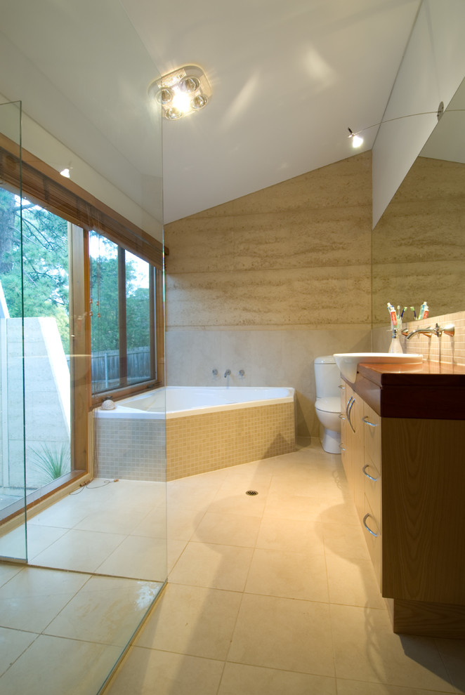 Design ideas for a contemporary master bathroom in Adelaide with flat-panel cabinets, dark wood cabinets, a corner tub, beige tile, beige walls, a curbless shower, a two-piece toilet, ceramic floors, an integrated sink, wood benchtops and an open shower.