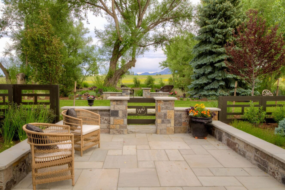 This is an example of a large farmhouse back patio in Denver with natural stone paving.