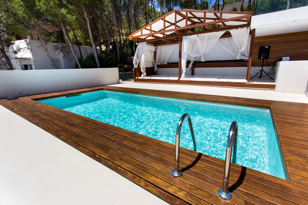 This is an example of a small mediterranean courtyard rectangular lap pool in Barcelona with a pool house and decking.