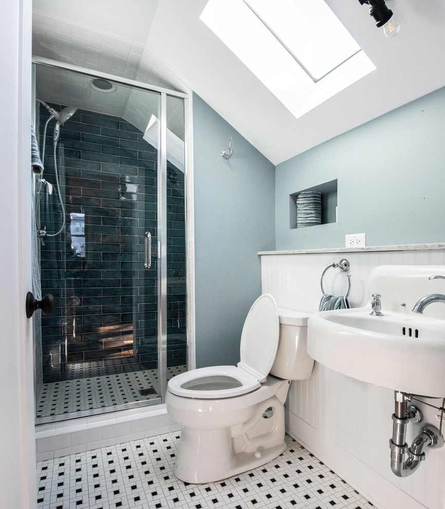 Small arts and crafts kids bathroom in Chicago with open cabinets, an alcove shower, a two-piece toilet, blue tile, porcelain tile, blue walls, mosaic tile floors, an integrated sink, solid surface benchtops, multi-coloured floor, a hinged shower door and white benchtops.