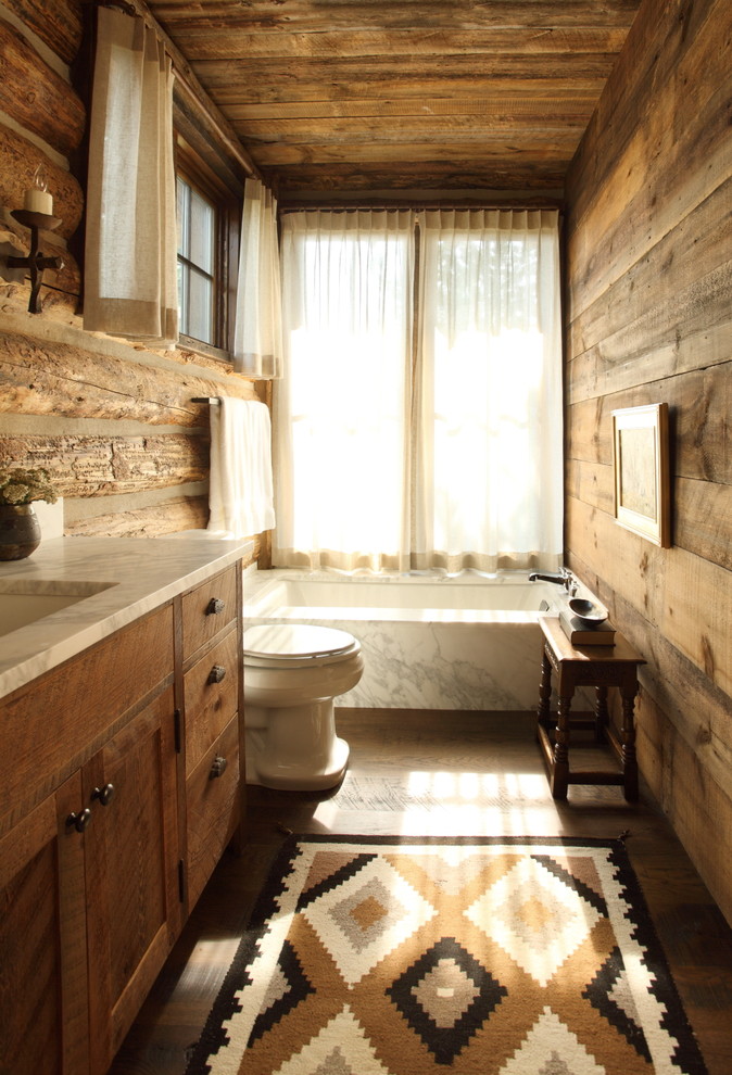 Design ideas for a mid-sized country 3/4 bathroom in Other with a two-piece toilet, brown walls, an undermount sink, marble benchtops, recessed-panel cabinets, medium wood cabinets, an undermount tub and medium hardwood floors.
