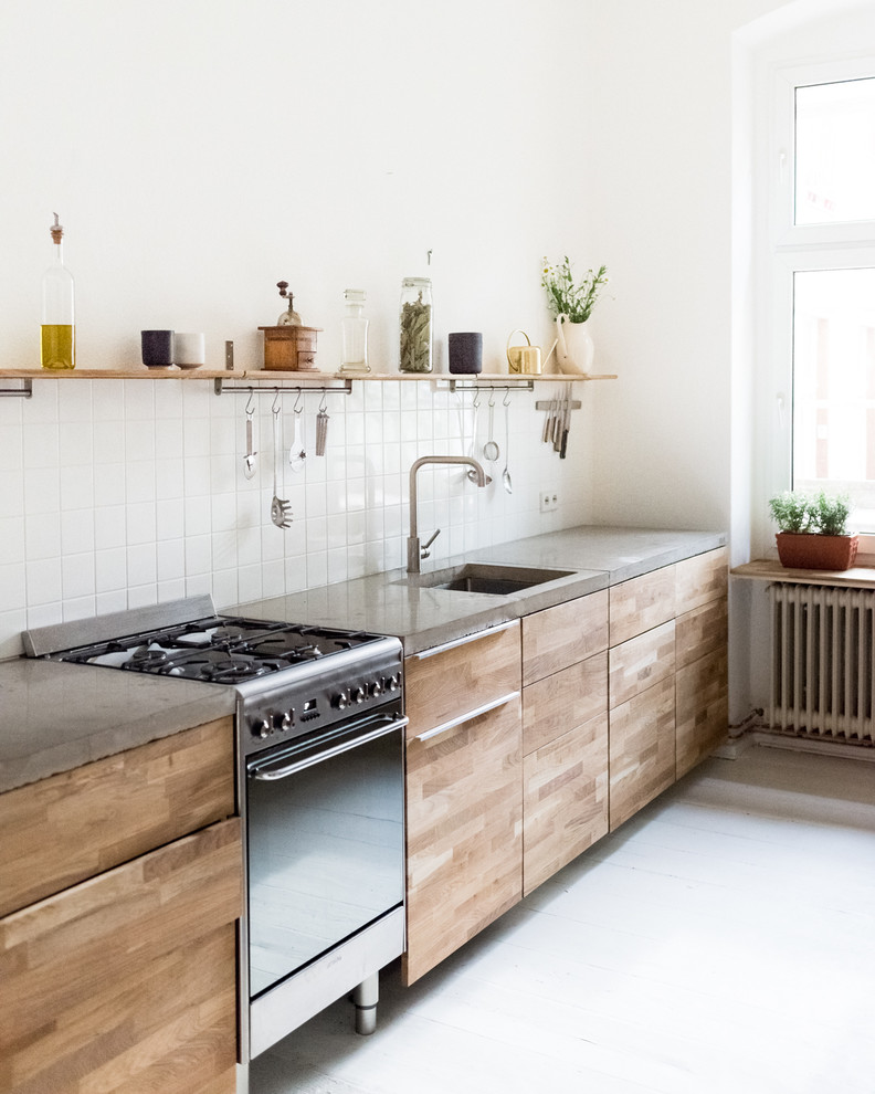 Inspiration for a contemporary single-wall kitchen in Berlin with flat-panel cabinets, medium wood cabinets, concrete benchtops, white splashback, ceramic splashback, stainless steel appliances, no island and a single-bowl sink.