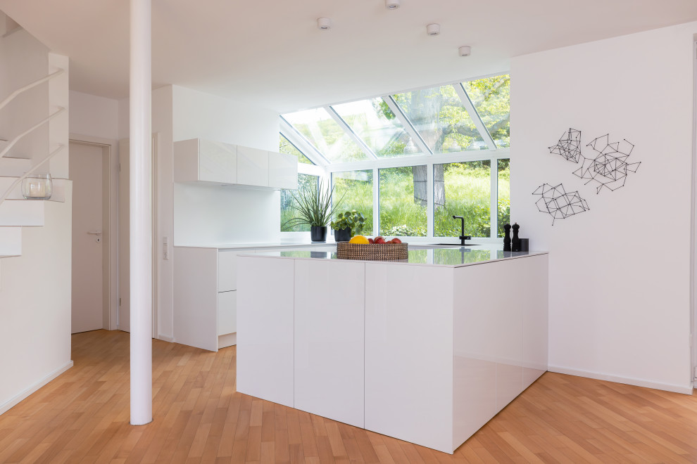 Design ideas for a mid-sized scandinavian u-shaped open plan kitchen in Frankfurt with a single-bowl sink, flat-panel cabinets, white cabinets, solid surface benchtops, white splashback, engineered quartz splashback, panelled appliances, medium hardwood floors, a peninsula, brown floor and white benchtop.