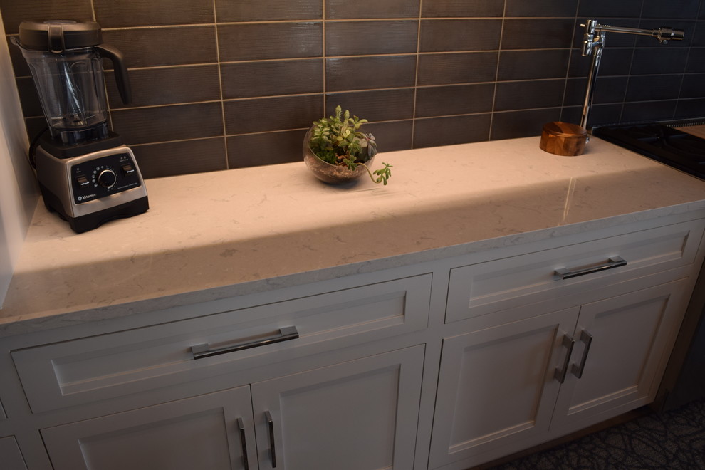 Inspiration for a large transitional l-shaped light wood floor and multicolored floor eat-in kitchen remodel in Chicago with beaded inset cabinets, white cabinets, quartz countertops, black backsplash, ceramic backsplash, stainless steel appliances and an island
