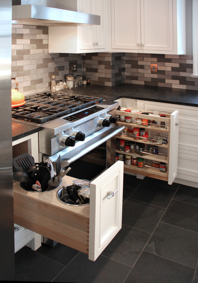 Inspiration for a mid-sized transitional l-shaped slate floor eat-in kitchen remodel in Boston with a farmhouse sink, raised-panel cabinets, white cabinets, granite countertops, metallic backsplash, metal backsplash, stainless steel appliances and an island