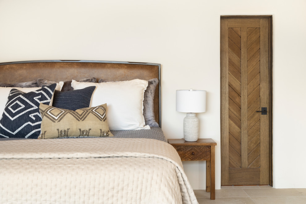 Diseño de dormitorio principal de estilo americano grande con suelo de baldosas de porcelana, estufa de leña, marco de chimenea de yeso, suelo beige y madera