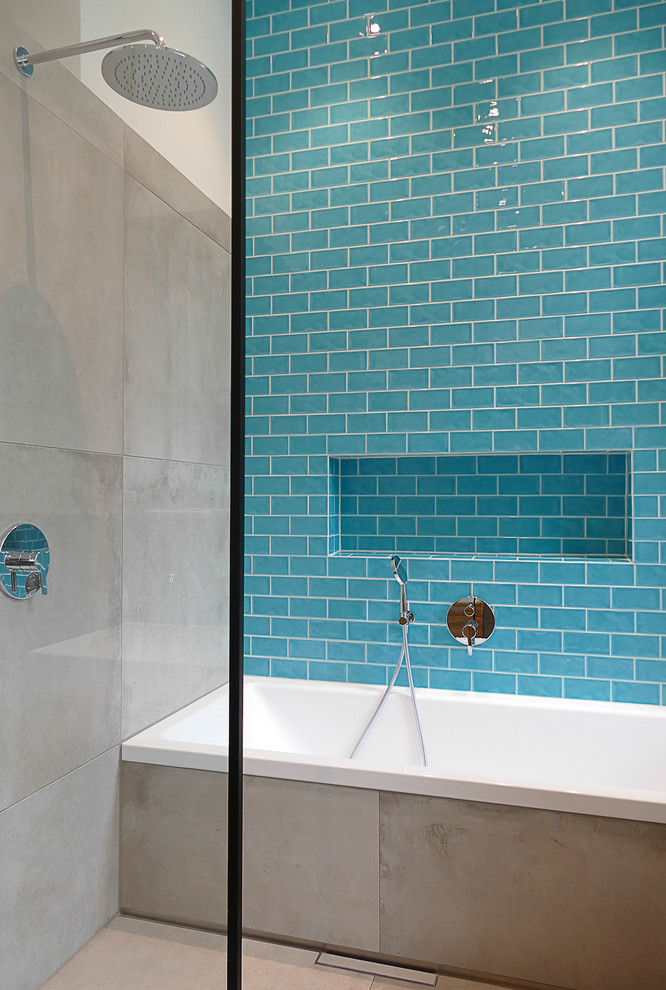 This is an example of a mid-sized contemporary bathroom in Berlin with a drop-in tub, an open shower, blue tile, subway tile, concrete floors, grey floor and an open shower.
