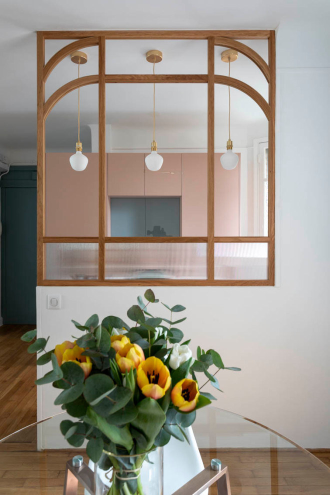 Cette image montre une petite cuisine américaine parallèle traditionnelle avec un évier encastré, des portes de placard rose, un plan de travail en bois, une crédence miroir, un électroménager en acier inoxydable et parquet clair.