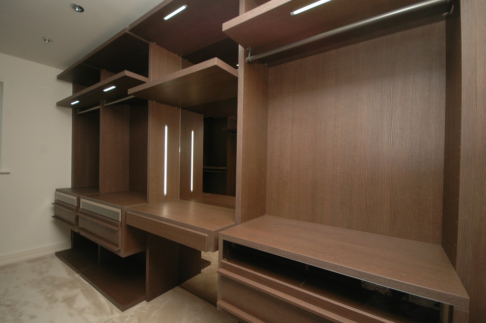 Design ideas for a mid-sized contemporary walk-in wardrobe in Dorset with dark wood cabinets.
