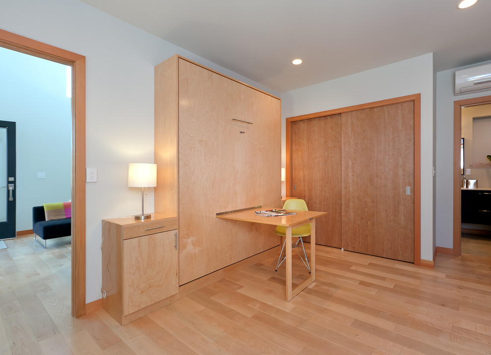 This is an example of a modern bedroom in Seattle with white walls and light hardwood floors.