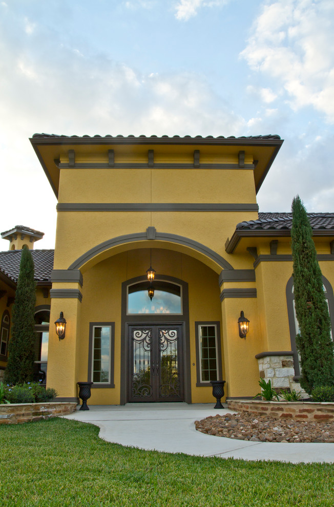 Inspiration for a large mediterranean one-storey stucco yellow exterior in Houston with a hip roof.
