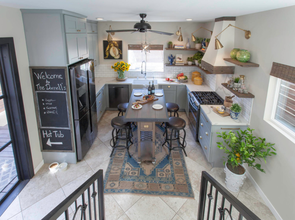 This is an example of a mid-sized industrial u-shaped eat-in kitchen in San Diego with a farmhouse sink, shaker cabinets, blue cabinets, quartz benchtops, white splashback, subway tile splashback, stainless steel appliances, with island, beige floor, white benchtop and travertine floors.