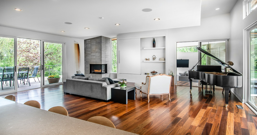 Photo of a mid-sized modern open concept living room in Other with white walls, dark hardwood floors, a two-sided fireplace, a concrete fireplace surround, a concealed tv and brown floor.
