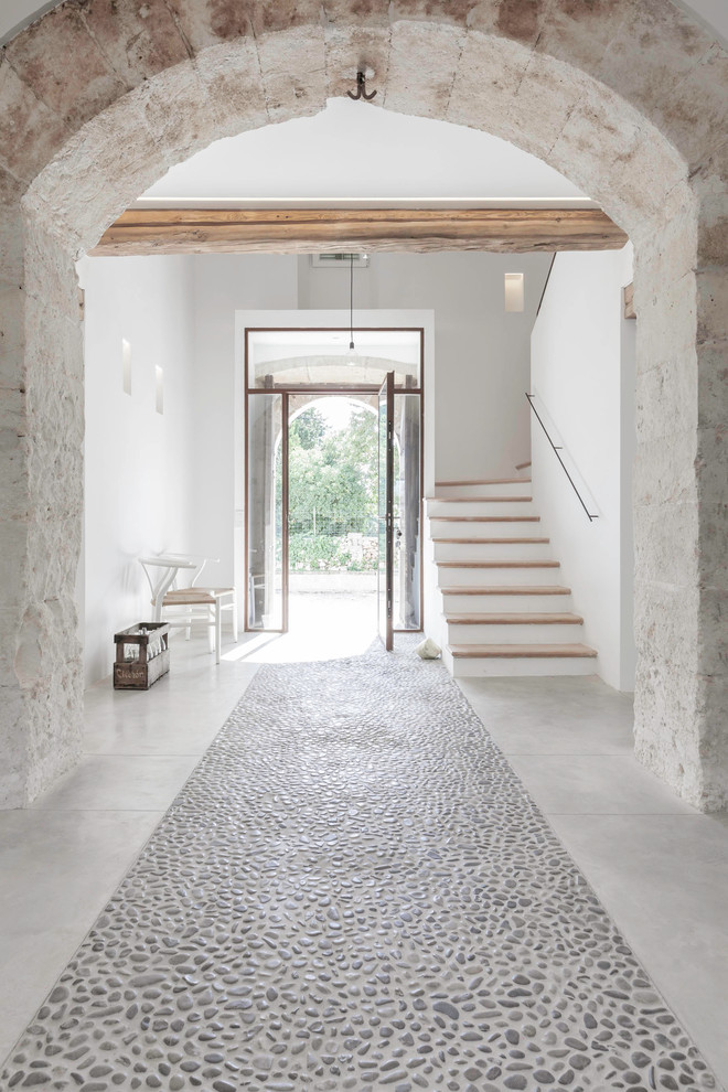 Photo of a large mediterranean entryway in Palma de Mallorca with white walls, a single front door and a glass front door.