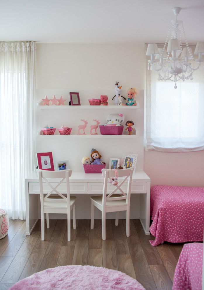 This is an example of a large transitional kids' bedroom for kids 4-10 years old and girls in Tel Aviv with white walls, medium hardwood floors and brown floor.