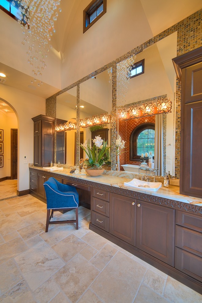 Photo of a large mediterranean master bathroom in Austin with a drop-in sink, recessed-panel cabinets, brown cabinets, a freestanding tub, orange tile, ceramic tile, beige walls, travertine floors, onyx benchtops and beige floor.