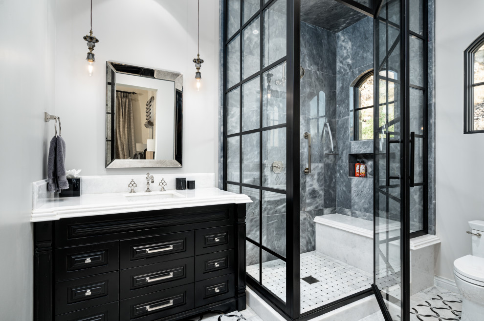 Foto på ett vit badrum, med luckor med upphöjd panel, svarta skåp, en hörndusch, grå kakel, vita väggar, ett undermonterad handfat, grått golv och dusch med gångjärnsdörr