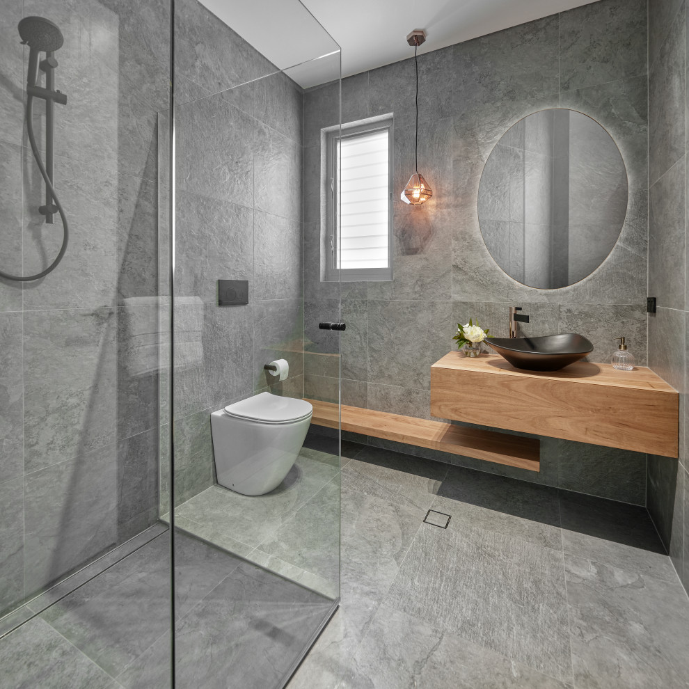 Bild på ett mellanstort funkis grå grått en-suite badrum, med släta luckor, vita skåp, ett fristående badkar, en dusch i en alkov, grå kakel, keramikplattor, grå väggar, klinkergolv i keramik, ett undermonterad handfat, bänkskiva i kvarts, grått golv och dusch med gångjärnsdörr