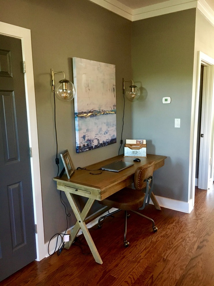 Mittelgroßes Industrial Arbeitszimmer mit grauer Wandfarbe, braunem Holzboden, freistehendem Schreibtisch und braunem Boden in Charlotte
