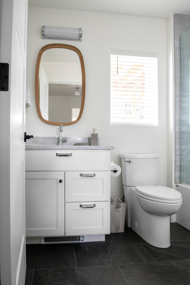 Idées déco pour une salle de bain moderne de taille moyenne avec un placard à porte shaker, des portes de placard blanches, une baignoire posée, un carrelage gris, des carreaux de céramique, un sol en ardoise, un plan de toilette en quartz modifié, un sol gris, une cabine de douche à porte battante, un plan de toilette gris, meuble simple vasque et meuble-lavabo encastré.