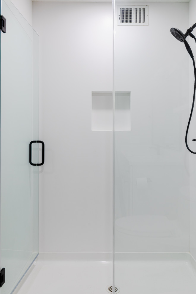 Inspiration pour une salle de bain vintage de taille moyenne avec un placard à porte shaker, des portes de placard blanches, une baignoire d'angle, WC à poser, un mur blanc, un sol en carrelage de céramique, un lavabo encastré, un plan de toilette en quartz modifié, un sol marron, une cabine de douche à porte battante, un plan de toilette blanc, meuble simple vasque, meuble-lavabo encastré et un mur en parement de brique.