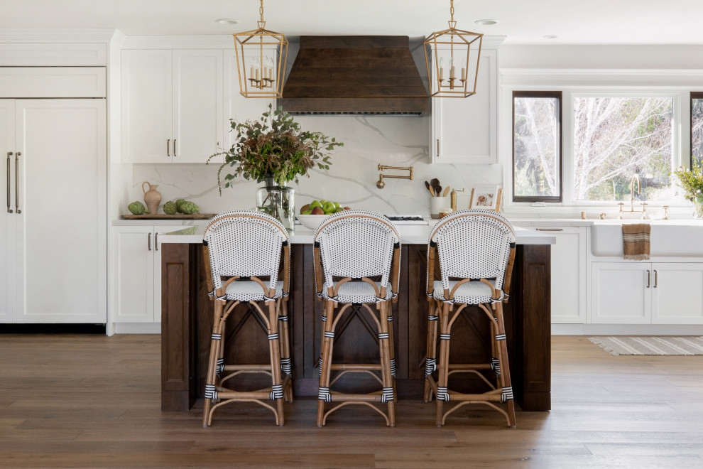 Inspiration for a large country kitchen in Los Angeles with with island, a farmhouse sink, shaker cabinets, white cabinets, white splashback, panelled appliances, medium hardwood floors and white benchtop.