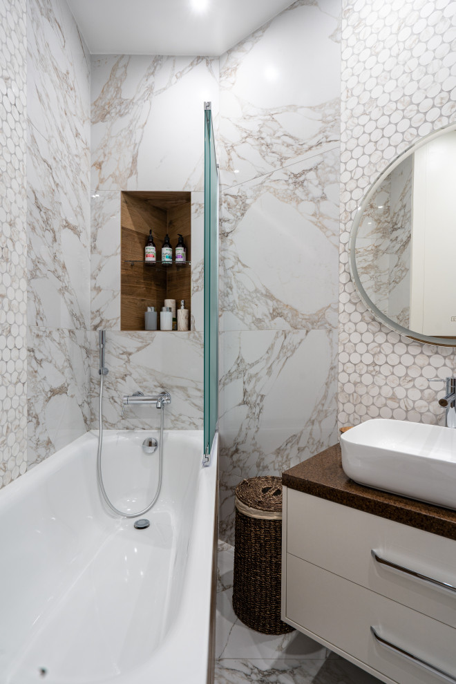 Modernes Badezimmer En Suite mit flächenbündigen Schrankfronten, grauen Schränken, Badewanne in Nische, Duschbadewanne, weißen Fliesen, brauner Waschtischplatte, Einzelwaschbecken und schwebendem Waschtisch in Moskau
