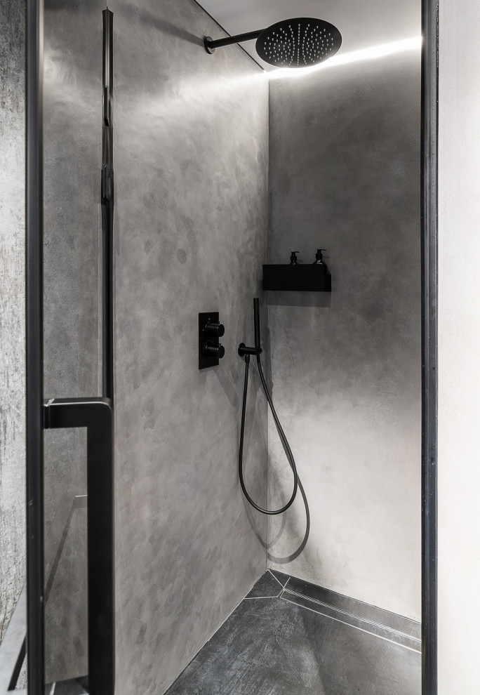 Свежая идея для дизайна: серо-белая ванная комната среднего размера в стиле лофт с плоскими фасадами, серыми фасадами, душем в нише, инсталляцией, черной плиткой, керамогранитной плиткой, серыми стенами, полом из керамогранита, душевой кабиной, подвесной раковиной, столешницей из бетона, серым полом, душем с распашными дверями, серой столешницей, зеркалом с подсветкой, тумбой под одну раковину, подвесной тумбой и панелями на стенах - отличное фото интерьера