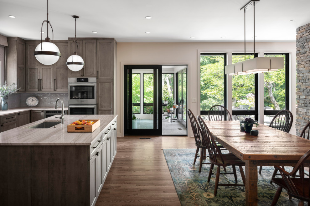 This is an example of a medium sized eclectic u-shaped open plan kitchen in Chicago with a submerged sink, recessed-panel cabinets, medium wood cabinets, quartz worktops, white splashback, ceramic splashback, stainless steel appliances, dark hardwood flooring, an island, brown floors and white worktops.