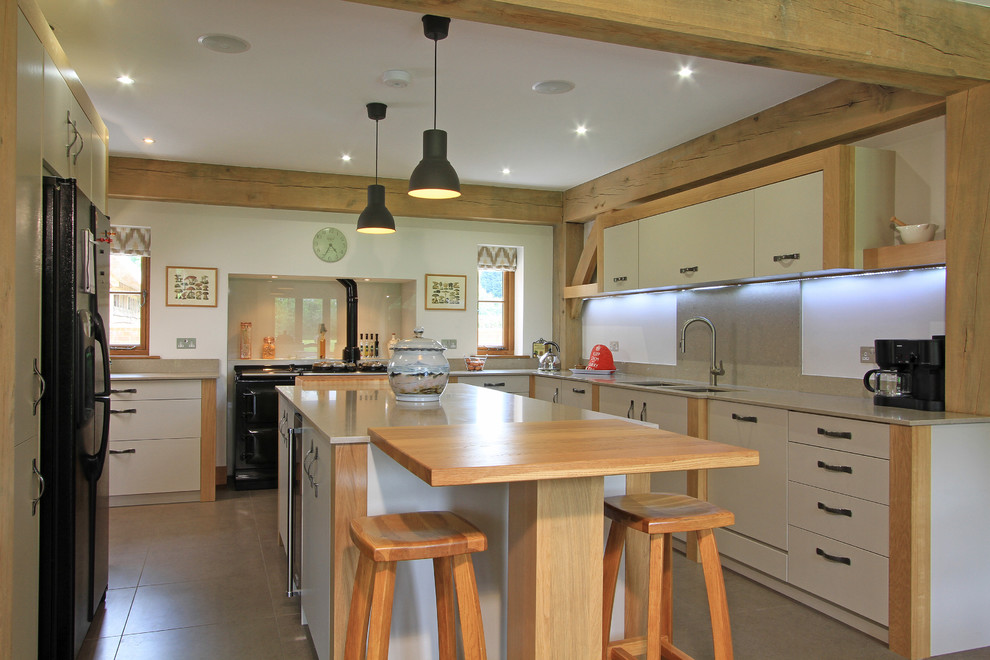 This is an example of a large contemporary l-shaped eat-in kitchen in Hampshire with an undermount sink, flat-panel cabinets, beige cabinets, quartz benchtops, grey splashback, stone slab splashback, black appliances, porcelain floors and with island.