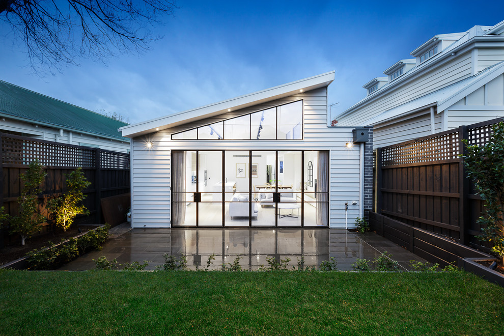 Contemporary one-storey white house exterior in Melbourne with vinyl siding and a shed roof.