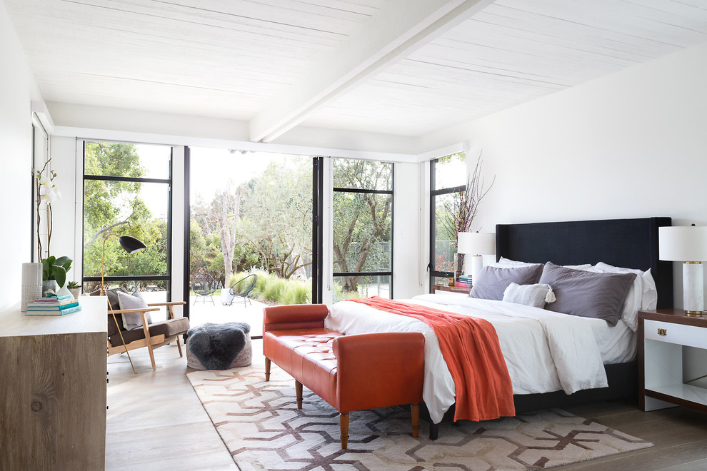 This is an example of a contemporary master bedroom in Los Angeles with white walls and light hardwood floors.