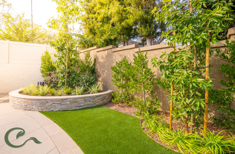 Large and australian native contemporary backyard full sun xeriscape in Orange County with with lawn edging, concrete pavers and a vinyl fence for summer.