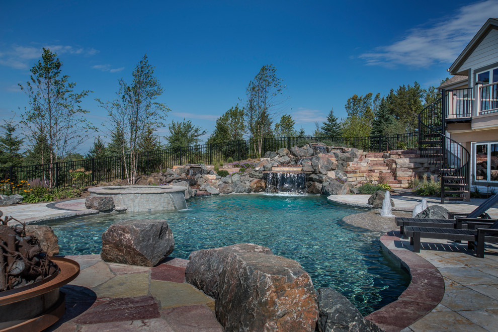 Inspiration for a mid-sized country backyard custom-shaped natural pool in Milwaukee with a hot tub and concrete pavers.