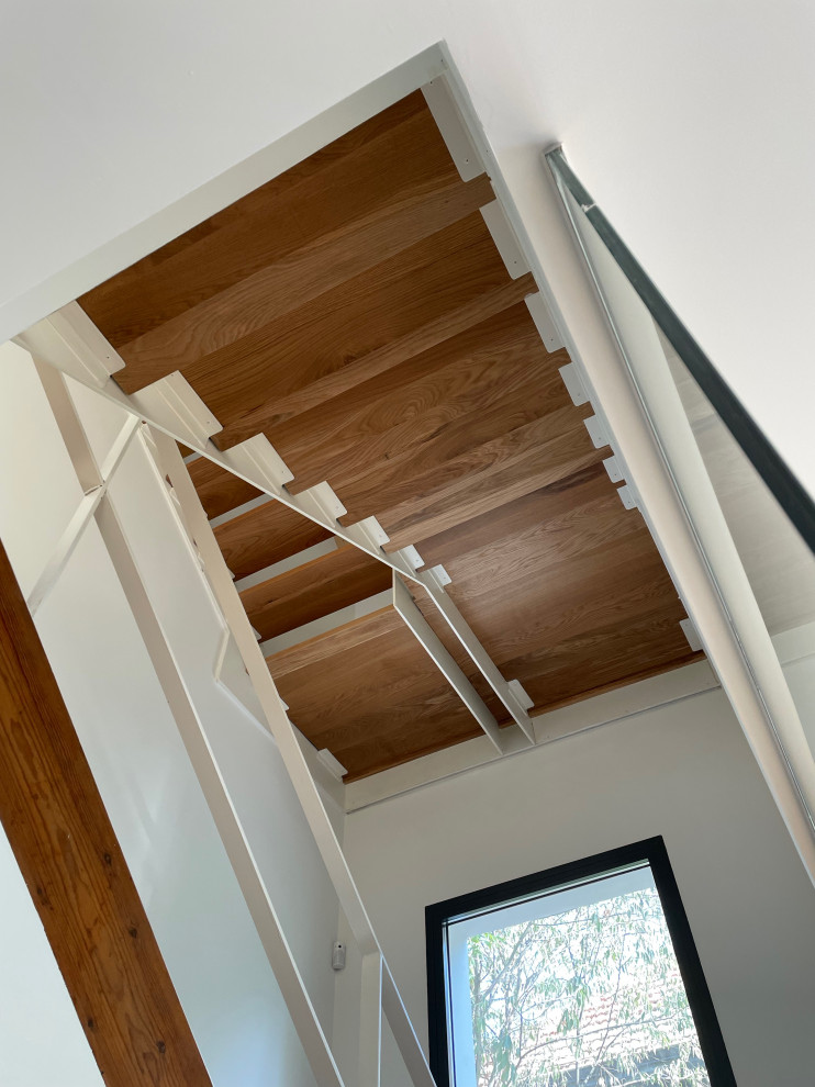 Inspiration for a large mediterranean wood u-shaped staircase in Madrid with open risers, metal railing and wallpaper.