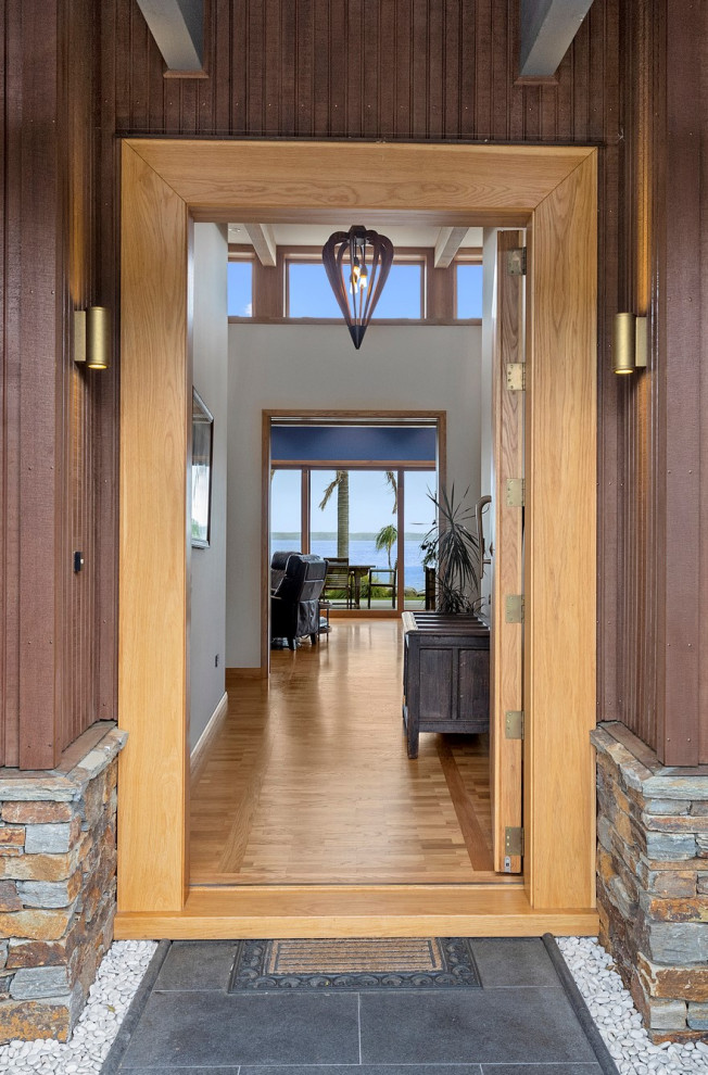 This is an example of a large modern foyer in Other with white walls, medium hardwood floors, a single front door, brown floor, a medium wood front door and exposed beam.