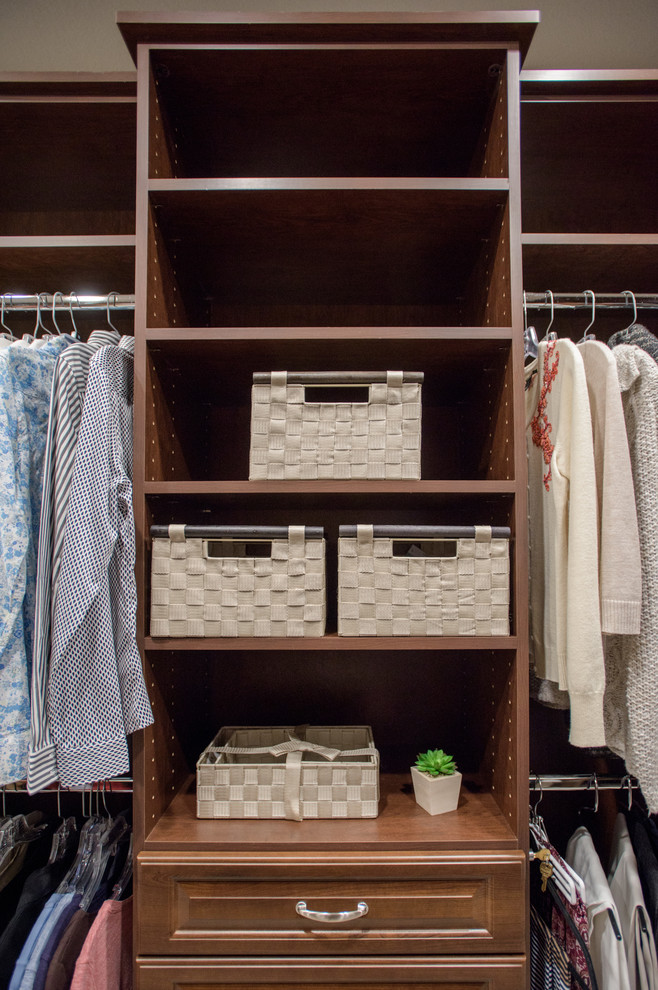Design ideas for a mid-sized traditional gender-neutral walk-in wardrobe in Denver with raised-panel cabinets, medium wood cabinets, carpet and beige floor.
