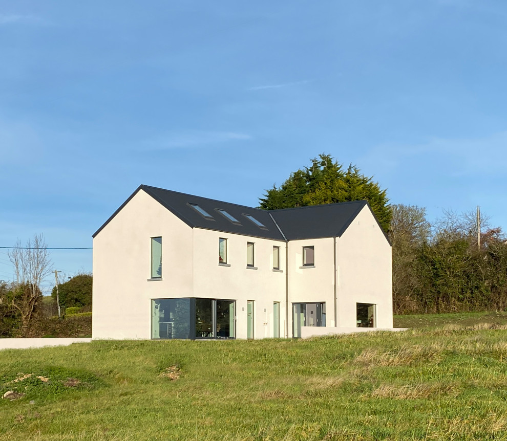 Modelo de fachada de casa blanca y gris actual de tamaño medio de dos plantas con revestimiento de metal, tejado a dos aguas y tejado de metal