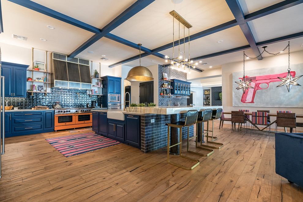 Photo of a large contemporary l-shaped eat-in kitchen in Phoenix with a farmhouse sink, raised-panel cabinets, blue cabinets, green splashback, coloured appliances, medium hardwood floors, with island, brown floor and beige benchtop.