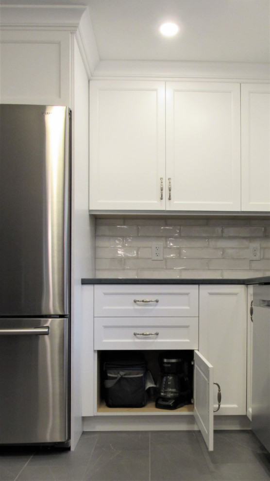 Example of a mid-sized transitional u-shaped porcelain tile and gray floor eat-in kitchen design in Boston with a farmhouse sink, recessed-panel cabinets, white cabinets, quartz countertops, gray backsplash, ceramic backsplash, stainless steel appliances, a peninsula and gray countertops