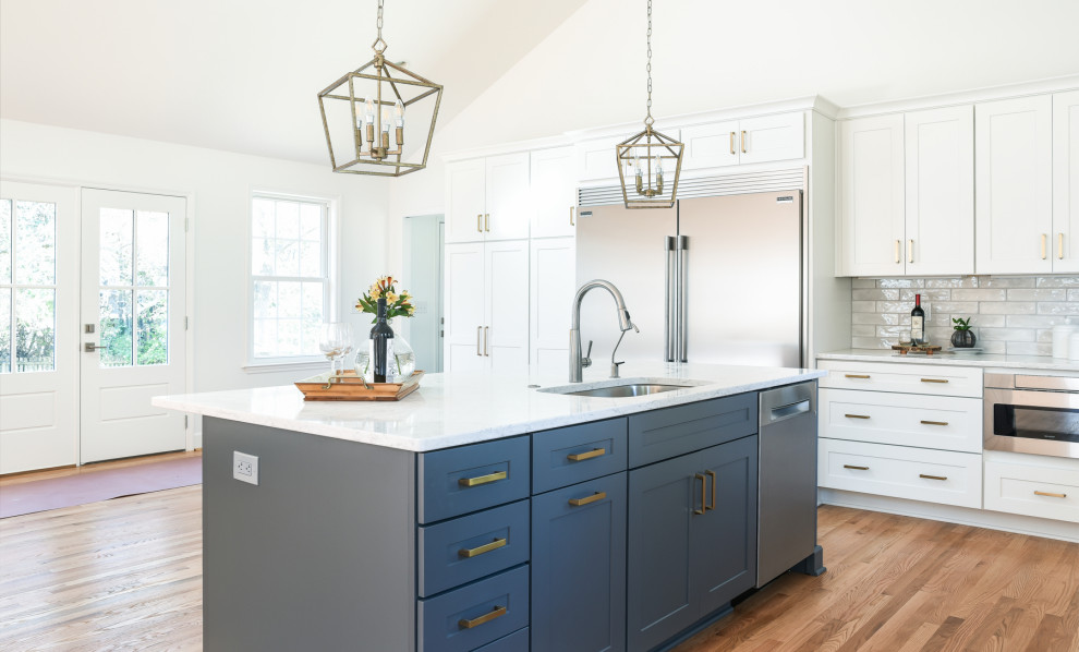 Design ideas for a large transitional eat-in kitchen in Nashville with an undermount sink, shaker cabinets, white cabinets, quartz benchtops, grey splashback, subway tile splashback, stainless steel appliances, light hardwood floors, with island, brown floor and white benchtop.