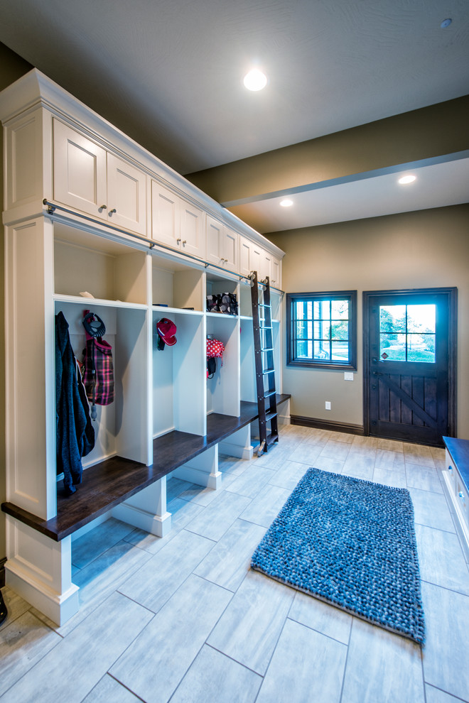 Example of a huge transitional porcelain tile mudroom design with beige walls and a dark wood front door