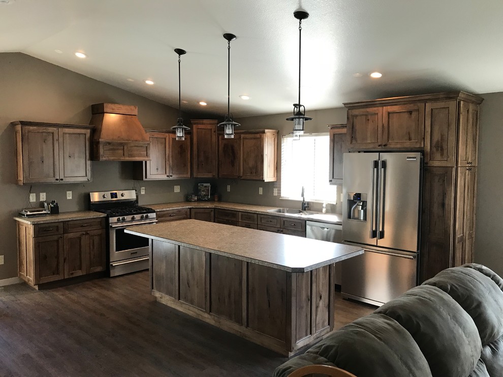 This is an example of a large country l-shaped open plan kitchen in Other with an undermount sink, medium wood cabinets, stainless steel appliances, with island, recessed-panel cabinets, laminate benchtops, medium hardwood floors and brown floor.